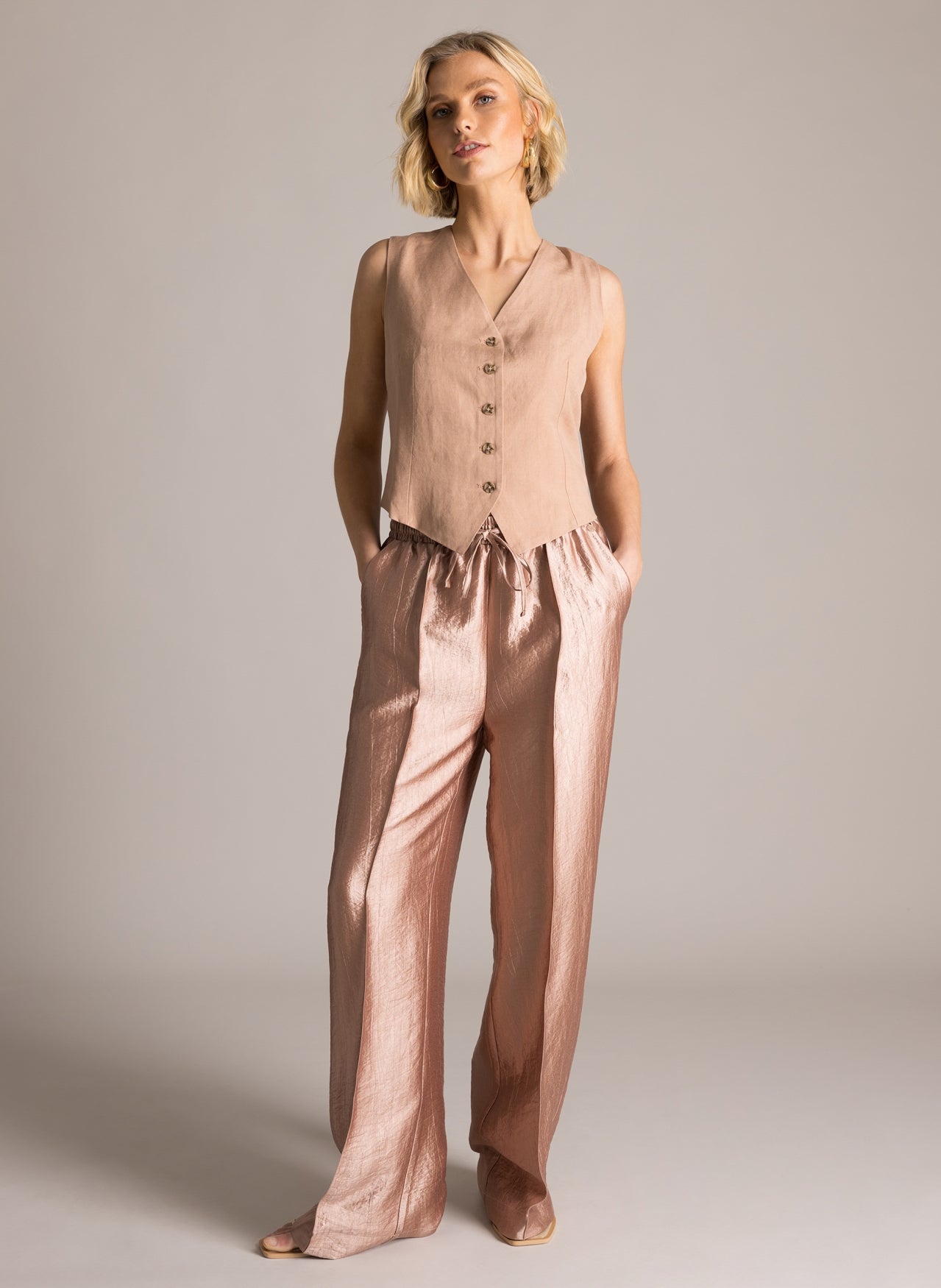 Klara kiiltävät housut suoralla lahkeella, joustava vyötärö ja sivutaskut